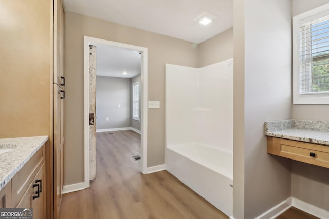 full bathroom featuring a wealth of natural light, vanity, baseboards, and wood finished floors