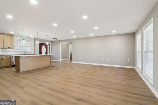 kitchen featuring backsplash, a kitchen island, dishwasher, recessed lighting, and light wood-style floors