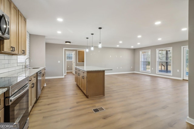 kitchen featuring visible vents, decorative backsplash, appliances with stainless steel finishes, light wood-style floors, and a sink