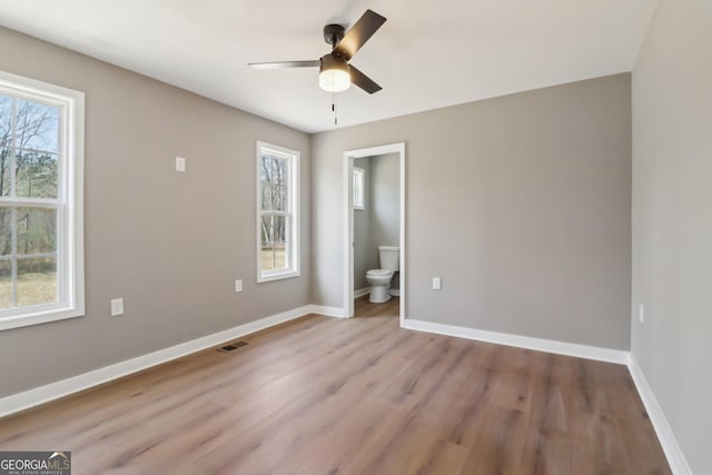 unfurnished bedroom featuring visible vents, connected bathroom, ceiling fan, baseboards, and wood finished floors