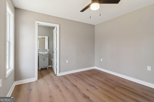 unfurnished bedroom featuring a ceiling fan, baseboards, light wood finished floors, and a sink