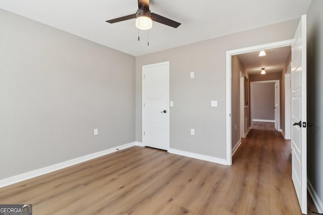 unfurnished bedroom featuring ceiling fan, baseboards, and wood finished floors