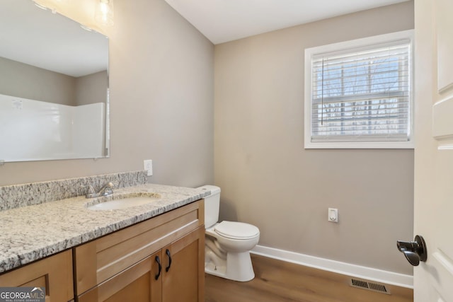 bathroom featuring visible vents, toilet, wood finished floors, baseboards, and vanity