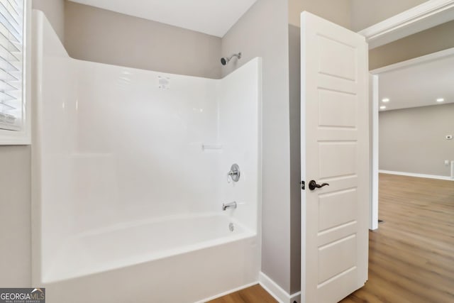 bathroom featuring shower / bathing tub combination, baseboards, and wood finished floors