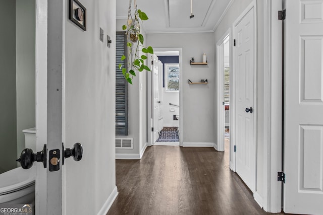 corridor with dark wood finished floors, visible vents, attic access, ornamental molding, and baseboards