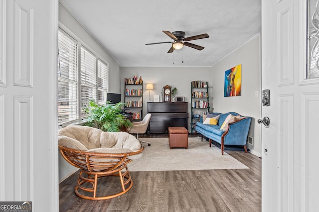 sitting room with crown molding, baseboards, ceiling fan, and wood finished floors