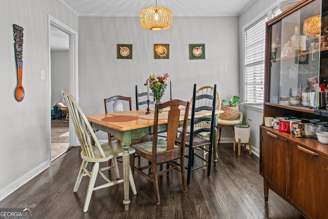 dining room featuring dark wood-type flooring, ornamental molding, and baseboards