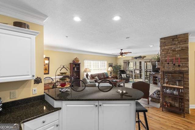 kitchen with a peninsula, light wood-style floors, white cabinetry, and a textured ceiling