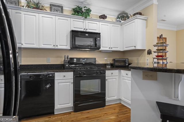 kitchen featuring black appliances, ornamental molding, and white cabinets