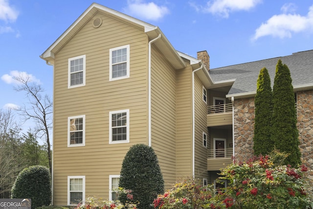 view of property exterior with a chimney and a balcony