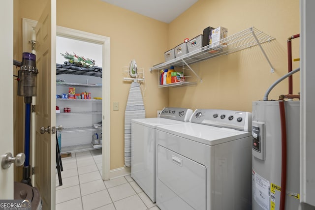 washroom with laundry area, light tile patterned floors, washer and clothes dryer, and electric water heater