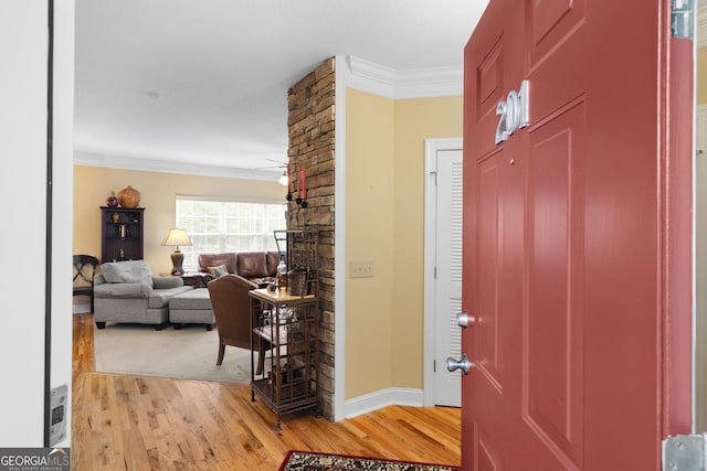 foyer featuring ornamental molding, light wood-type flooring, baseboards, and a ceiling fan