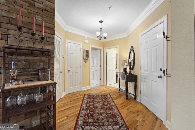 foyer with an inviting chandelier, baseboards, ornamental molding, and wood finished floors