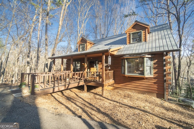 view of front of house with metal roof, a wooden deck, and log siding