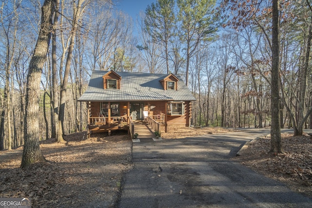 log-style house with metal roof, aphalt driveway, and a porch