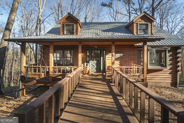 exterior space with covered porch, metal roof, and log siding