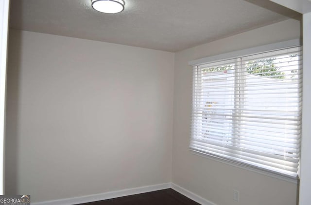 spare room with dark wood-style floors and baseboards