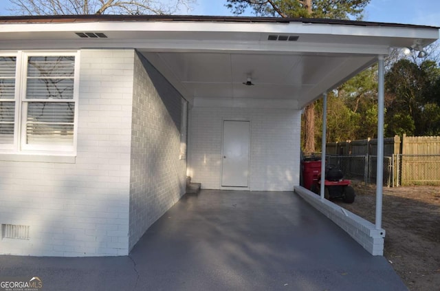 view of parking featuring an attached carport and fence