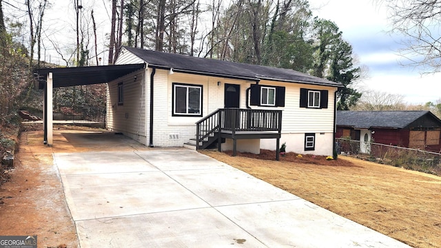 view of front of property with concrete driveway, a carport, a front lawn, and fence