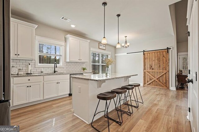 1312 Mcgarity Rd, Temple, GA 30179 - kitchen with a barn door, a sink, white cabinetry, backsplash, and plenty of natural light