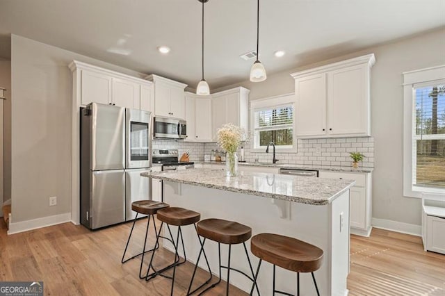 1312 Mcgarity Rd, Temple, GA 30179 - kitchen with stainless steel appliances, baseboards, light wood finished floors, white cabinets, and backsplash