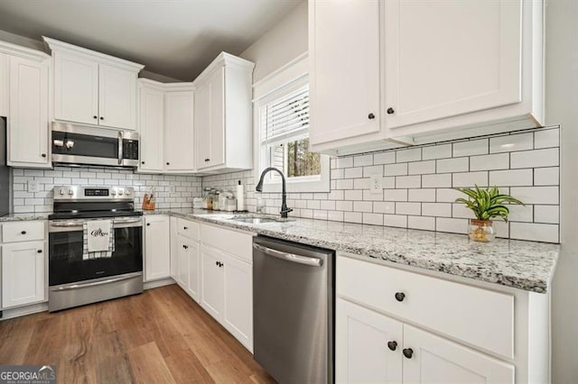 1312 Mcgarity Rd, Temple, GA 30179 - kitchen featuring stainless steel appliances, a sink, white cabinets, wood finished floors, and backsplash