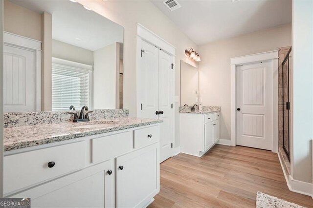 1312 Mcgarity Rd, Temple, GA 30179 - full bathroom featuring wood finished floors, two vanities, a stall shower, and baseboards