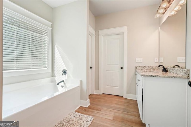 1312 Mcgarity Rd, Temple, GA 30179 - full bathroom with wood finished floors, a garden tub, vanity, and baseboards