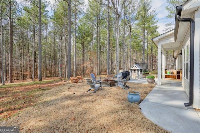 1312 Mcgarity Rd, Temple, GA 30179 - view of yard with an outdoor fire pit, a patio area, an outbuilding, and a wooded view