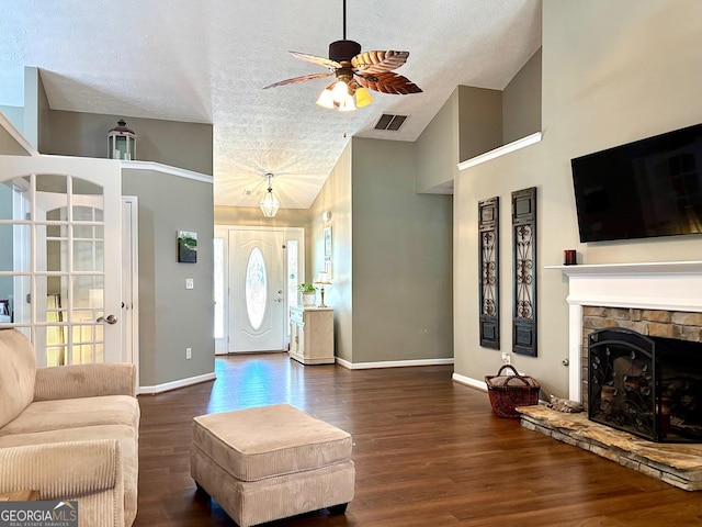 living room with a textured ceiling, a fireplace, wood finished floors, visible vents, and baseboards