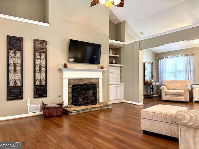 unfurnished living room with a stone fireplace, wood finished floors, visible vents, and a ceiling fan