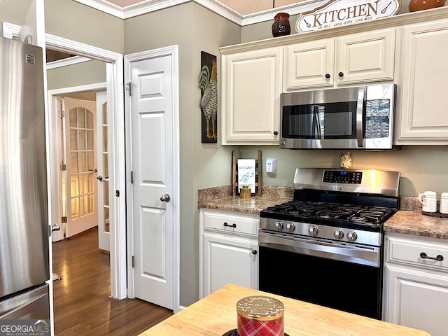 kitchen featuring ornamental molding, appliances with stainless steel finishes, dark wood-style floors, and white cabinetry