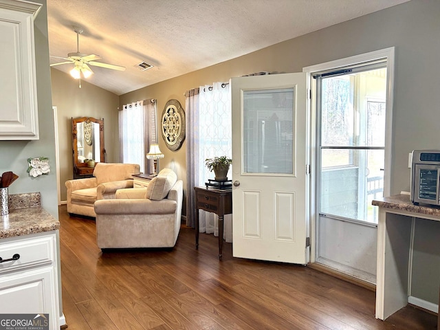 living room with lofted ceiling, dark wood-style floors, visible vents, and a textured ceiling