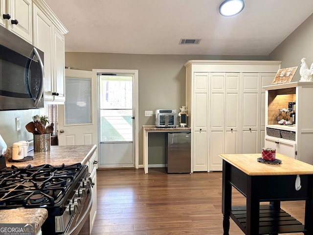 kitchen with visible vents, dark wood-style floors, appliances with stainless steel finishes, light countertops, and white cabinetry