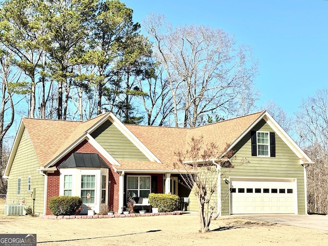 view of front of house featuring driveway, a garage, roof with shingles, central air condition unit, and brick siding