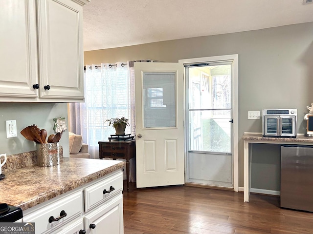 kitchen with dark wood-style flooring, white cabinets, a textured ceiling, and fridge