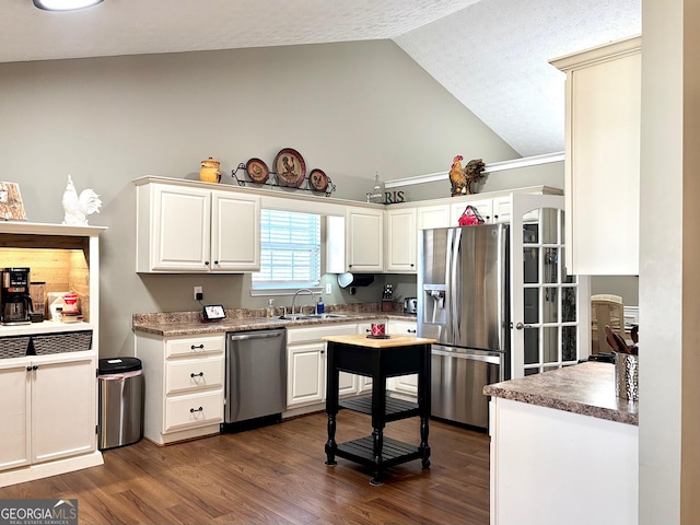 kitchen featuring stainless steel appliances, lofted ceiling, white cabinets, and dark wood finished floors