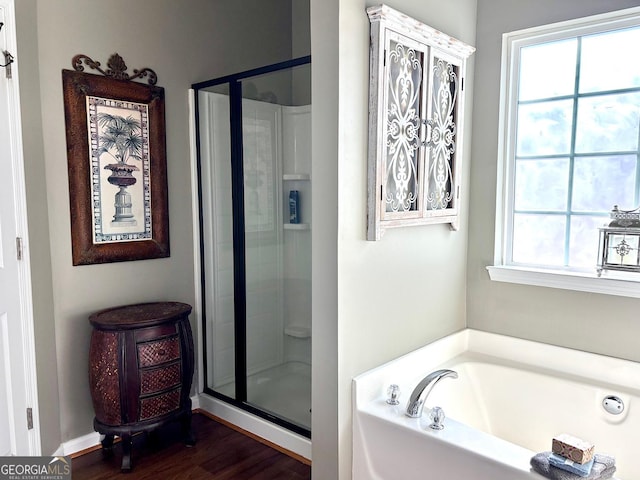 bathroom with a stall shower, a garden tub, and wood finished floors