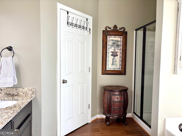 full bathroom featuring baseboards, a shower stall, vanity, and wood finished floors