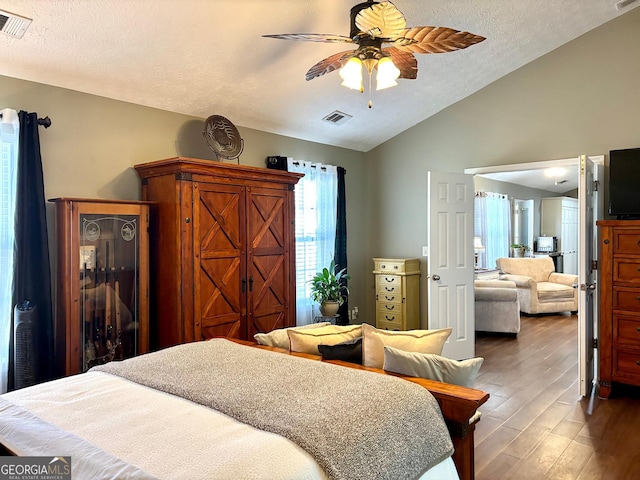 bedroom with visible vents, vaulted ceiling, a textured ceiling, and wood finished floors