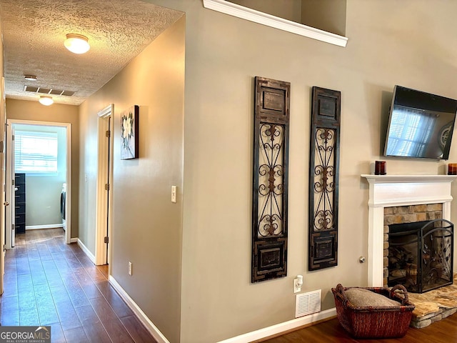 hallway featuring dark wood-style floors, visible vents, and a textured ceiling