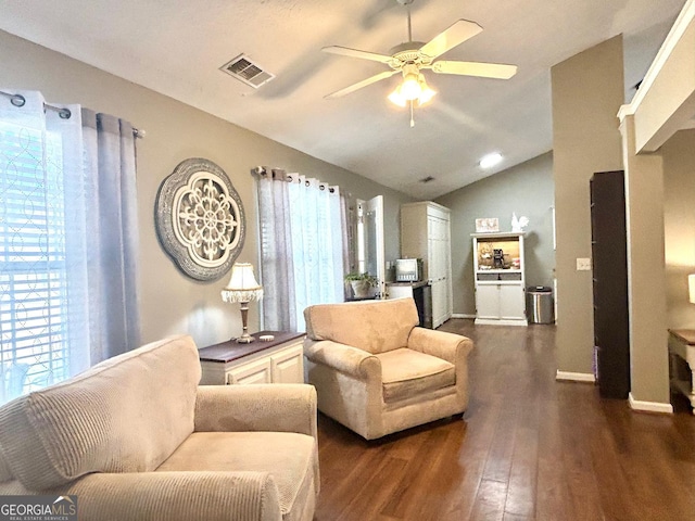 living room featuring dark wood-style flooring, visible vents, a ceiling fan, vaulted ceiling, and baseboards