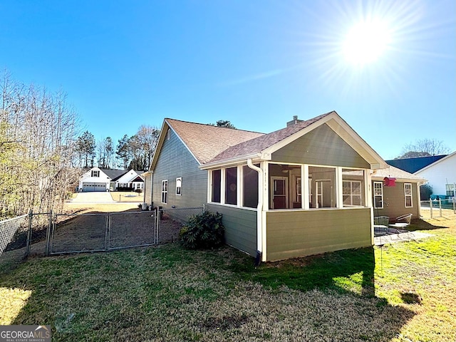 view of side of property featuring a sunroom, fence, and a lawn