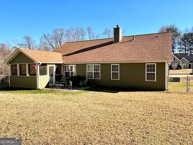 rear view of house with a yard, roof with shingles, fence, and a chimney