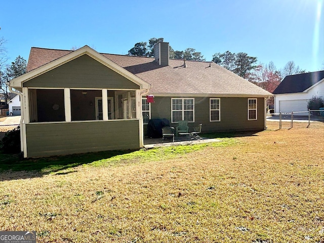 rear view of house with a sunroom, a lawn, a chimney, and a patio