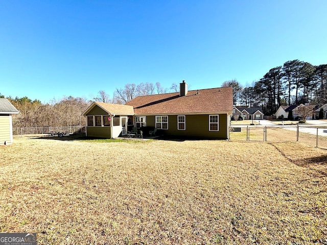 rear view of house with a gate, a lawn, a chimney, and fence