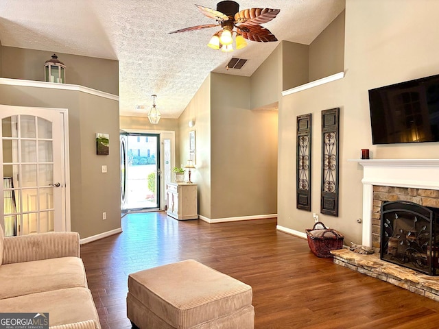 living area with a fireplace, wood finished floors, a ceiling fan, visible vents, and baseboards