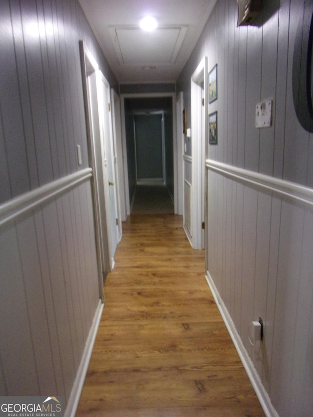 hallway with attic access and wood finished floors