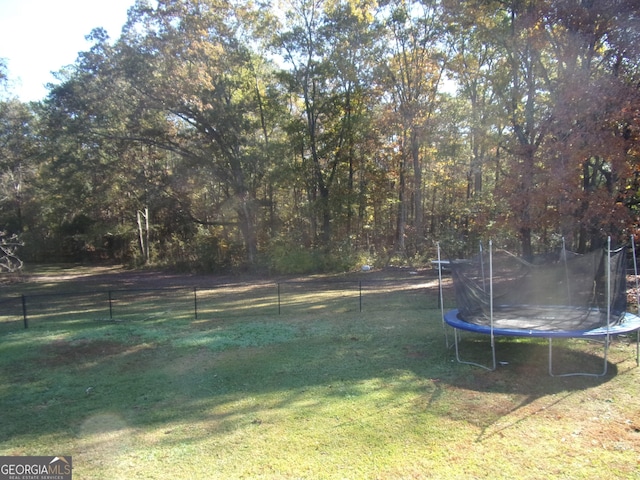 view of yard with a trampoline and fence