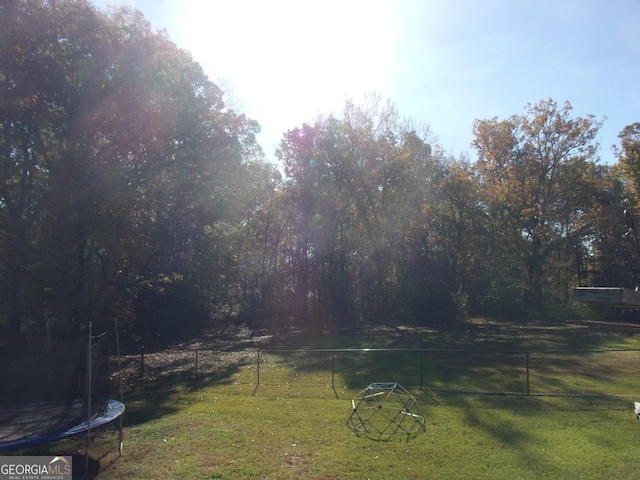 view of yard with a trampoline and fence